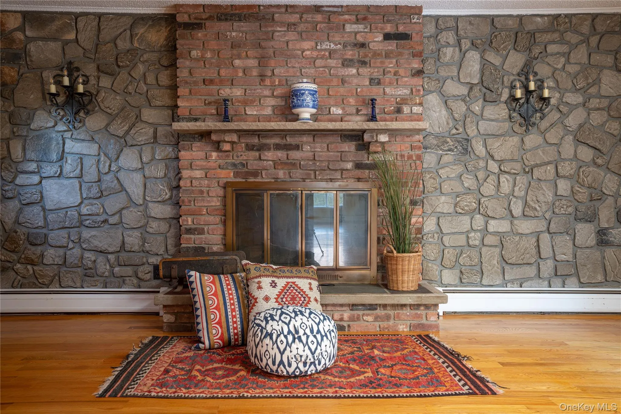 Detailed view of a fireplace, a baseboard heating unit, and wood finished floors Detailed view of a fireplace, a baseboard heating unit, and wood finished floors