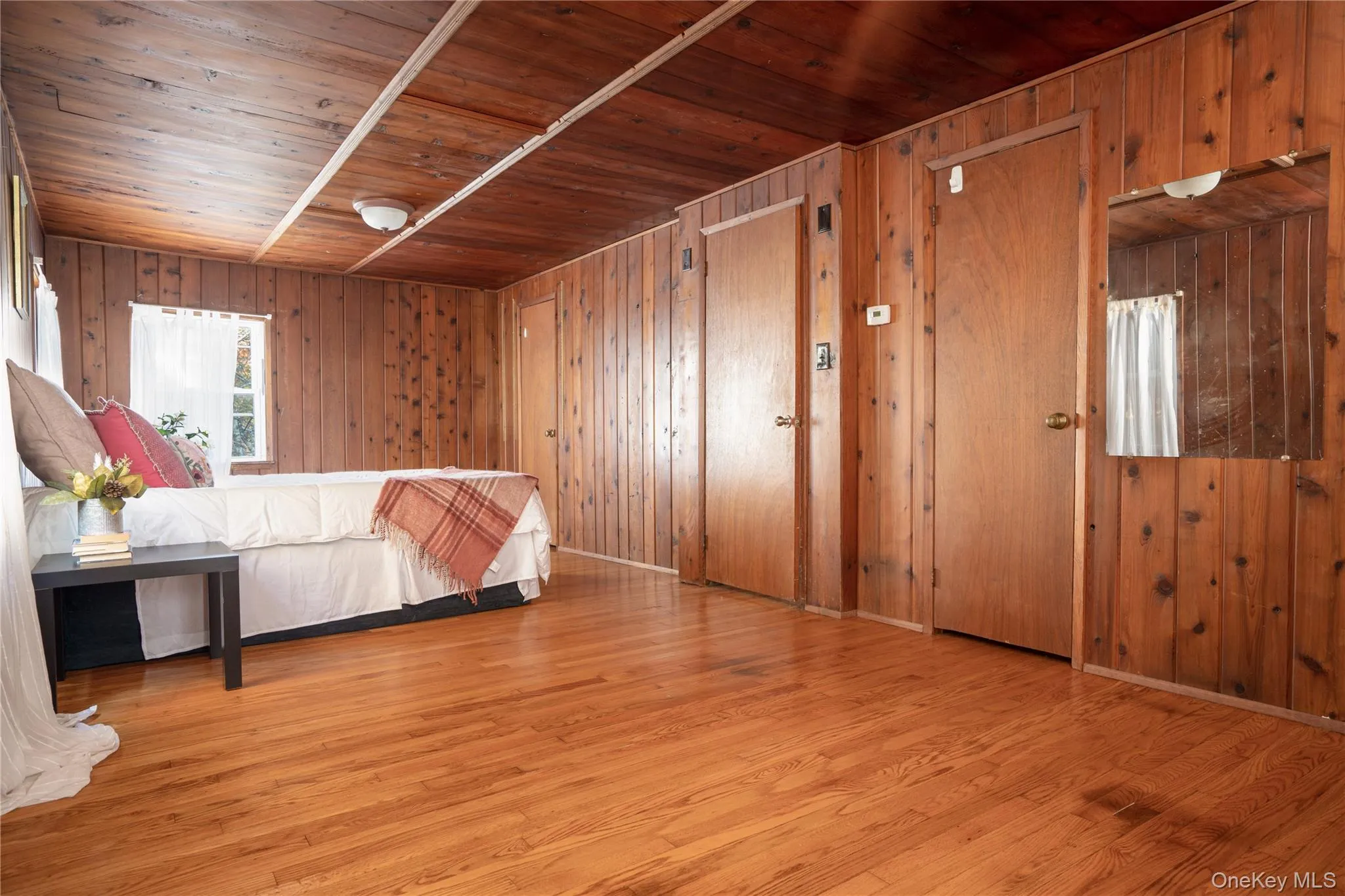 Unfurnished bedroom with wood ceiling, light wood-style floors, and wood walls Unfurnished bedroom with wood ceiling, light wood-style floors, and wood walls