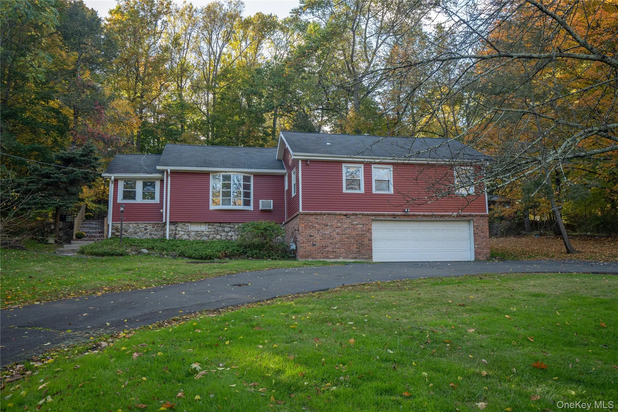 View of front of house featuring driveway, a front lawn, a garage, and view of wooded area View of front of house featuring driveway, a front lawn, a garage, and view of wooded area