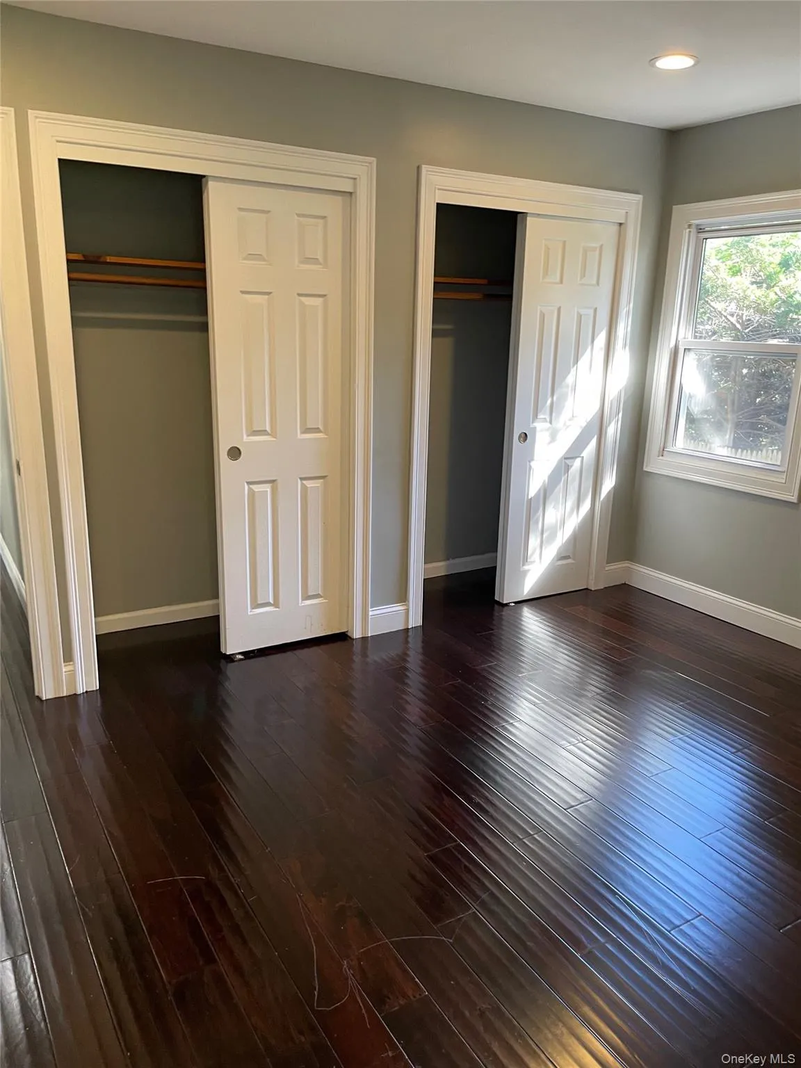Unfurnished bedroom with two closets, dark wood finished floors, and recessed lighting Unfurnished bedroom with two closets, dark wood finished floors, and recessed lighting