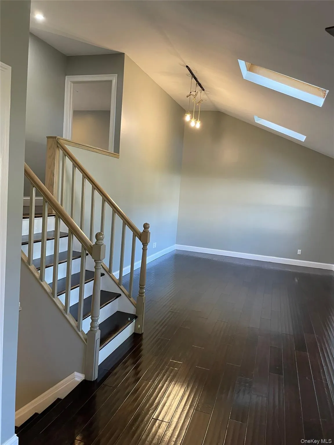 Stairs featuring a skylight, wood finished floors, and lofted ceiling Stairs featuring a skylight, wood finished floors, and lofted ceiling