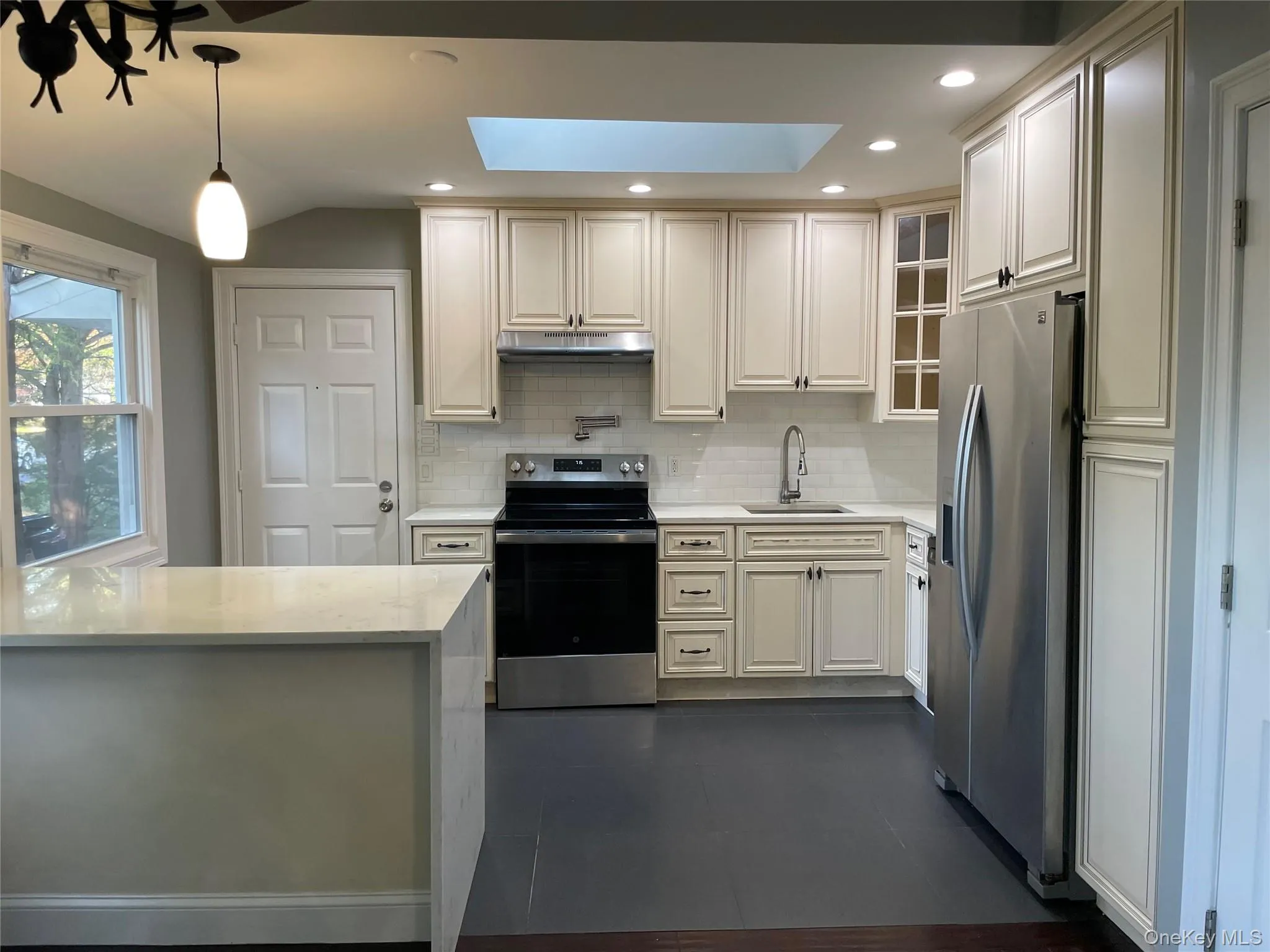 Kitchen with stainless steel appliances, tasteful backsplash, a skylight, light stone counters, and recessed lighting Kitchen with stainless steel appliances, tasteful backsplash, a skylight, light stone counters, and recessed lighting