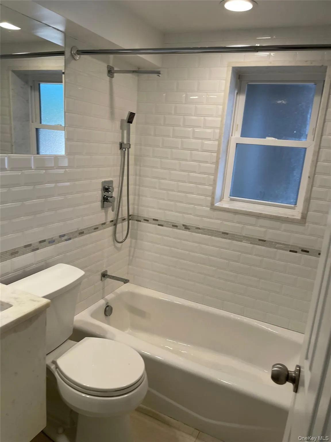 Bathroom with tile walls,  shower combination, vanity, recessed lighting, and tile patterned floors Bathroom with tile walls,  shower combination, vanity, recessed lighting, and tile patterned floors