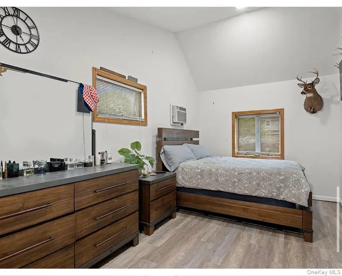 Bedroom with vaulted ceiling, light wood finished floors, and a wall mounted AC Bedroom with vaulted ceiling, light wood finished floors, and a wall mounted AC