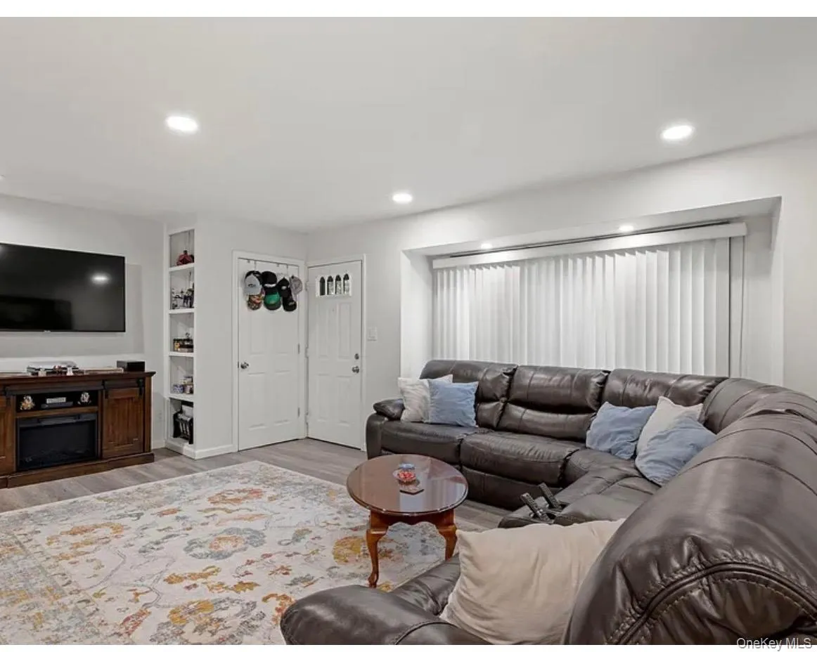 Living room featuring recessed lighting, wood finished floors, and built in shelves Living room featuring recessed lighting, wood finished floors, and built in shelves