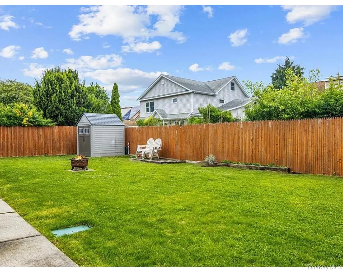 Fenced backyard featuring an outdoor fire pit and a storage unit Fenced backyard featuring an outdoor fire pit and a storage unit