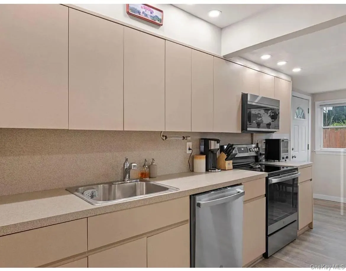 Kitchen featuring stainless steel appliances, light countertops, recessed lighting, light wood finished floors, and modern cabinets Kitchen featuring stainless steel appliances, light countertops, recessed lighting, light wood finished floors, and modern cabinets