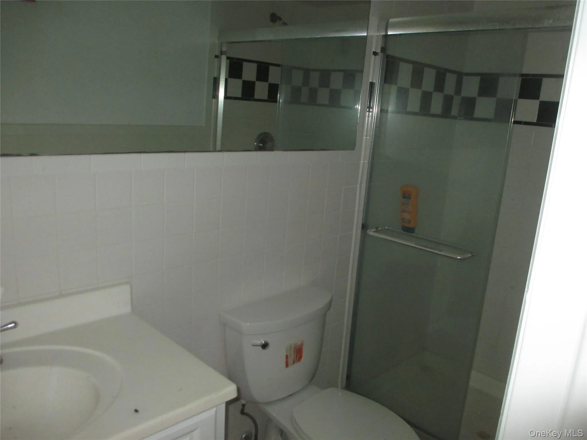 Full bathroom with tile walls, vanity, and a shower stall Full bathroom with tile walls, vanity, and a shower stall
