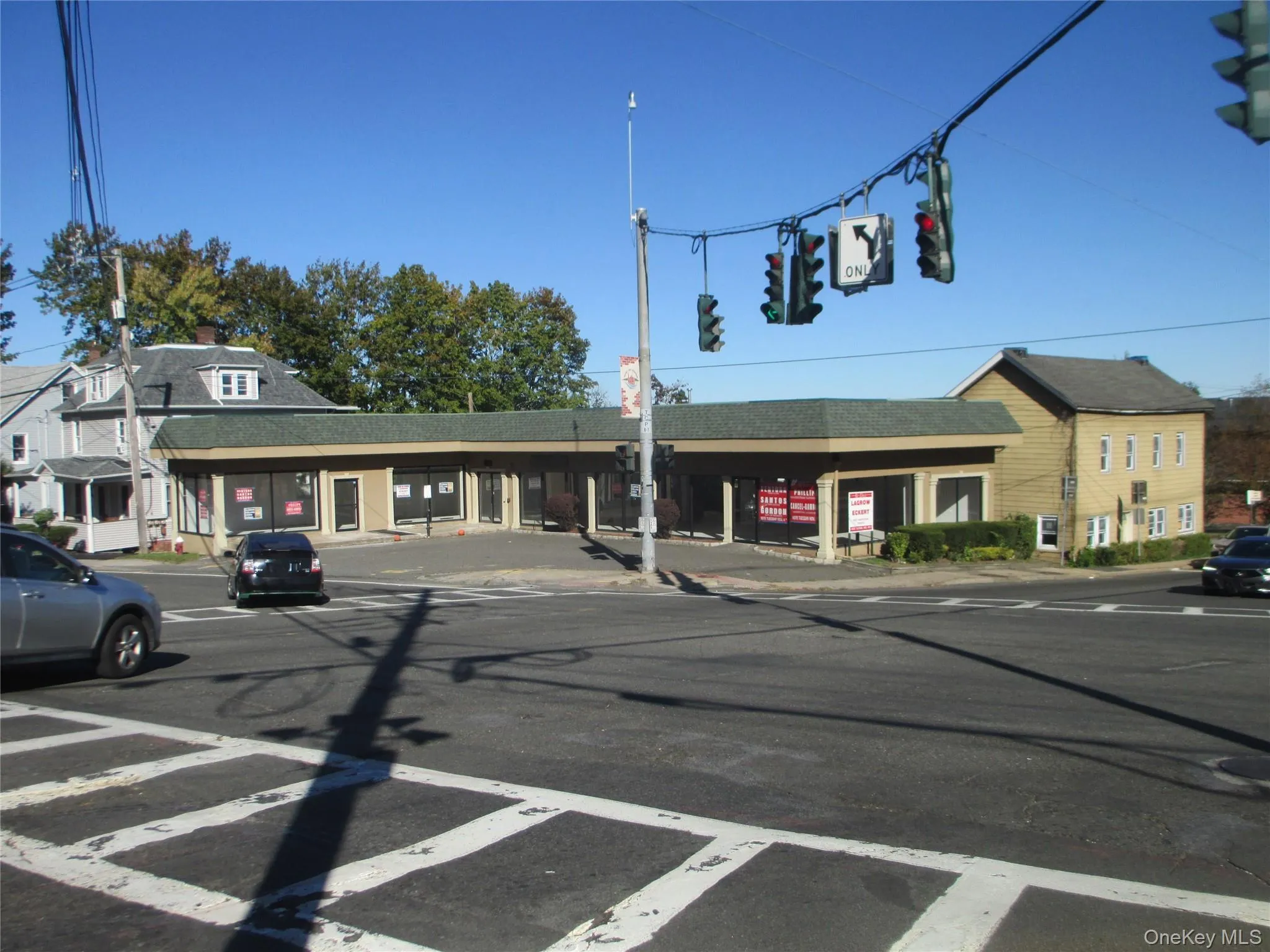 View of asphalt road featuring traffic lights, curbs, and sidewalks View of asphalt road featuring traffic lights, curbs, and sidewalks