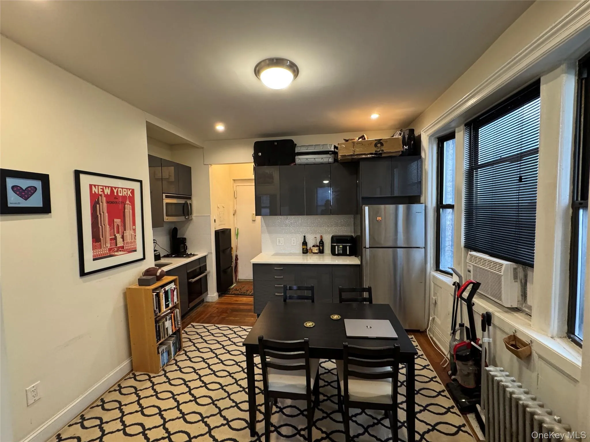Kitchen featuring appliances with stainless steel finishes, radiator heating unit, dark cabinetry, light countertops, and tasteful backsplash Kitchen featuring appliances with stainless steel finishes, radiator heating unit, dark cabinetry, light countertops, and tasteful backsplash