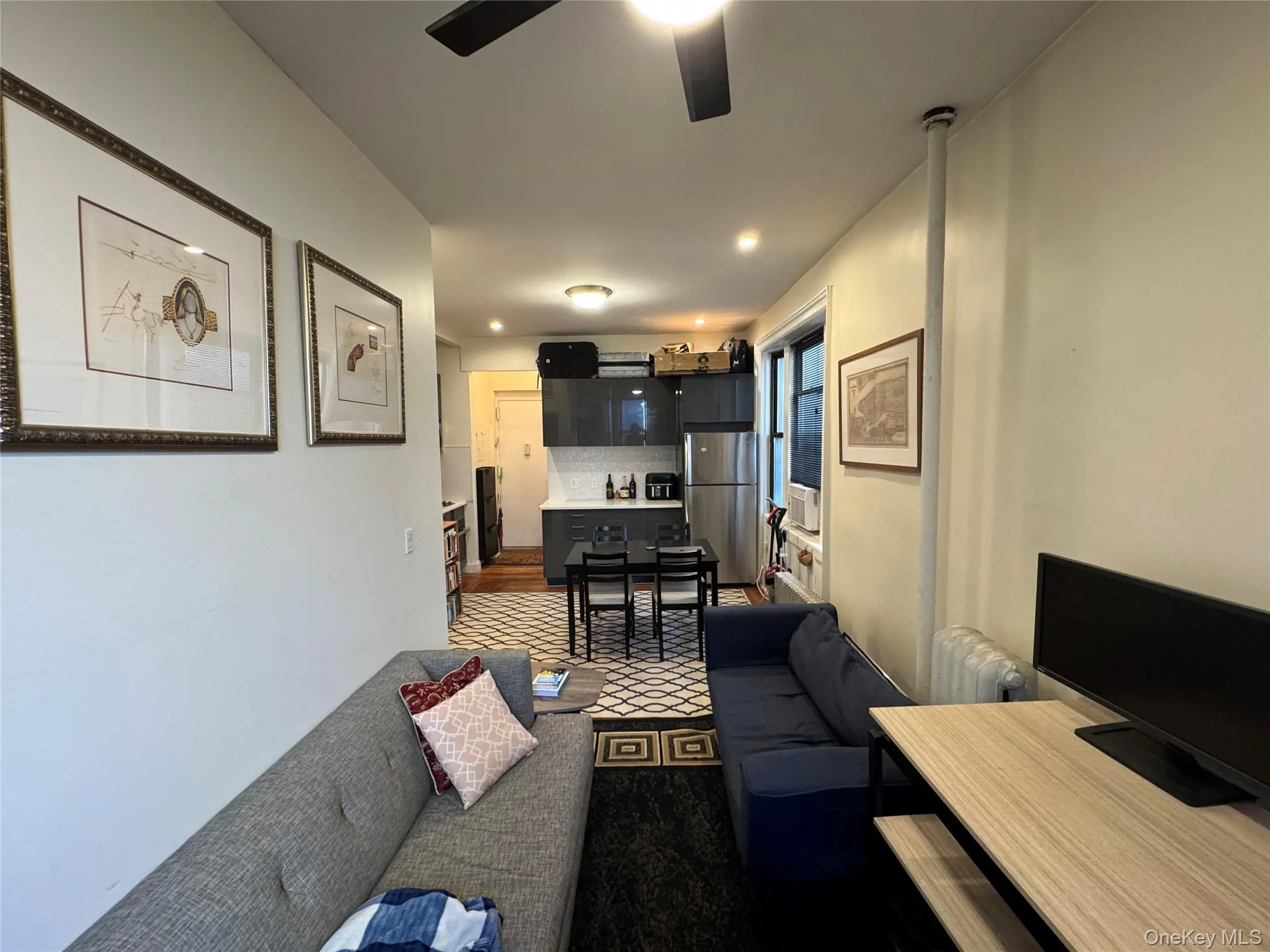 Living room with a ceiling fan, dark colored carpet, and radiator Living room with a ceiling fan, dark colored carpet, and radiator