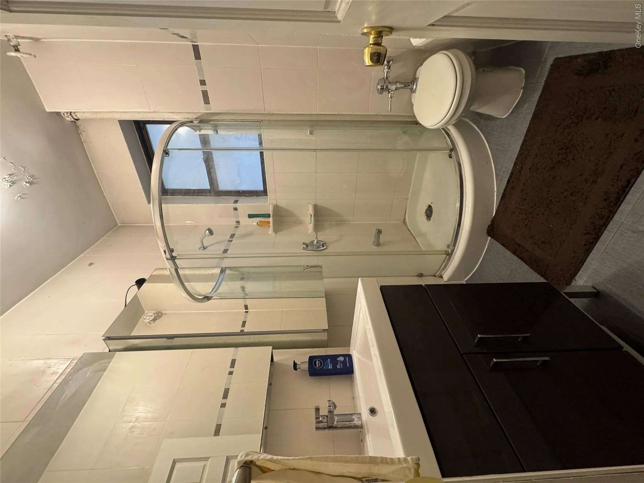 Full bathroom with tile walls, vanity, a stall shower, and tile patterned floors Full bathroom with tile walls, vanity, a stall shower, and tile patterned floors