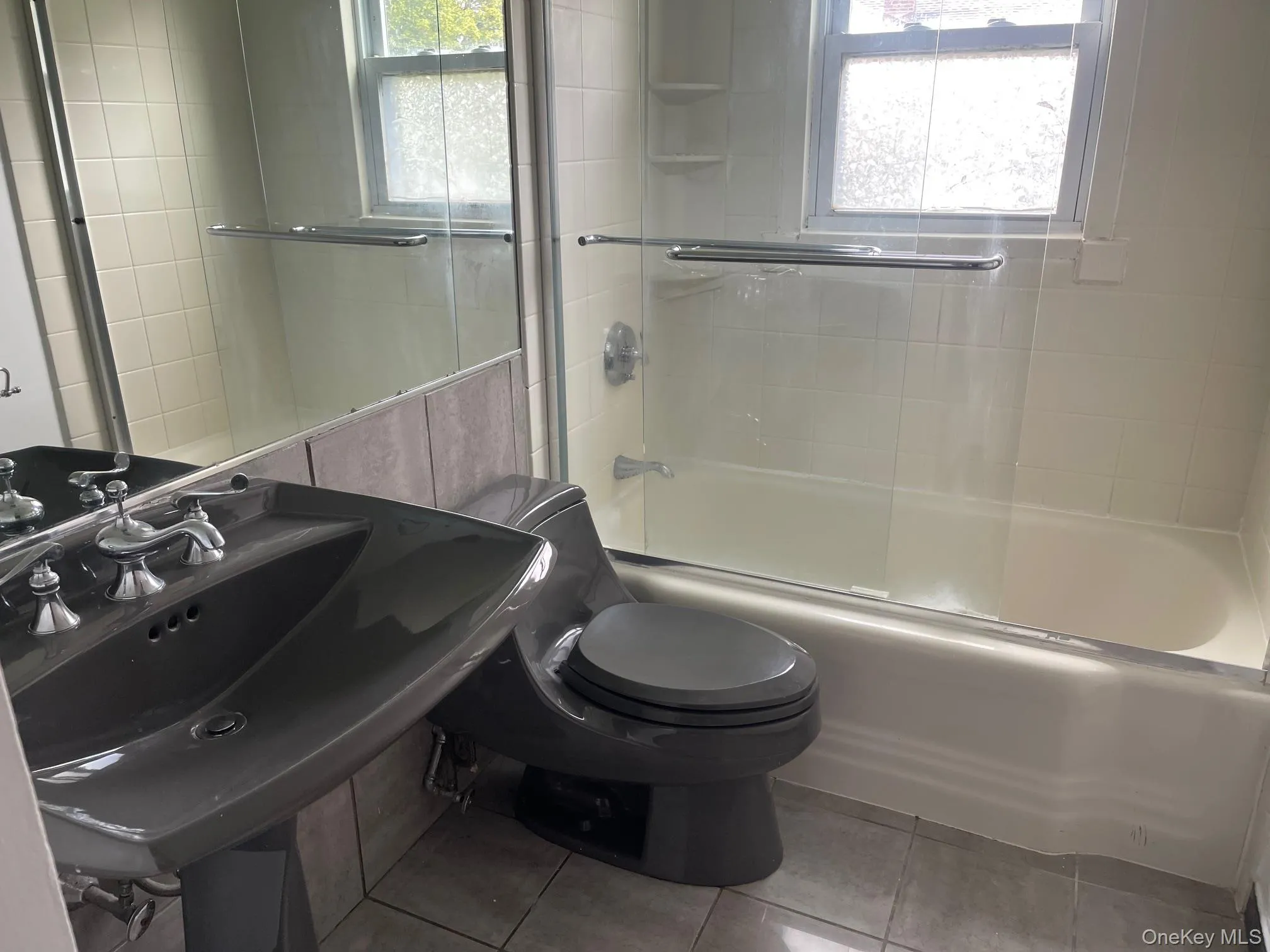 Full bathroom featuring enclosed tub / shower combo, plenty of natural light, tile walls, and tile patterned flooring Full bathroom featuring enclosed tub / shower combo, plenty of natural light, tile walls, and tile patterned flooring