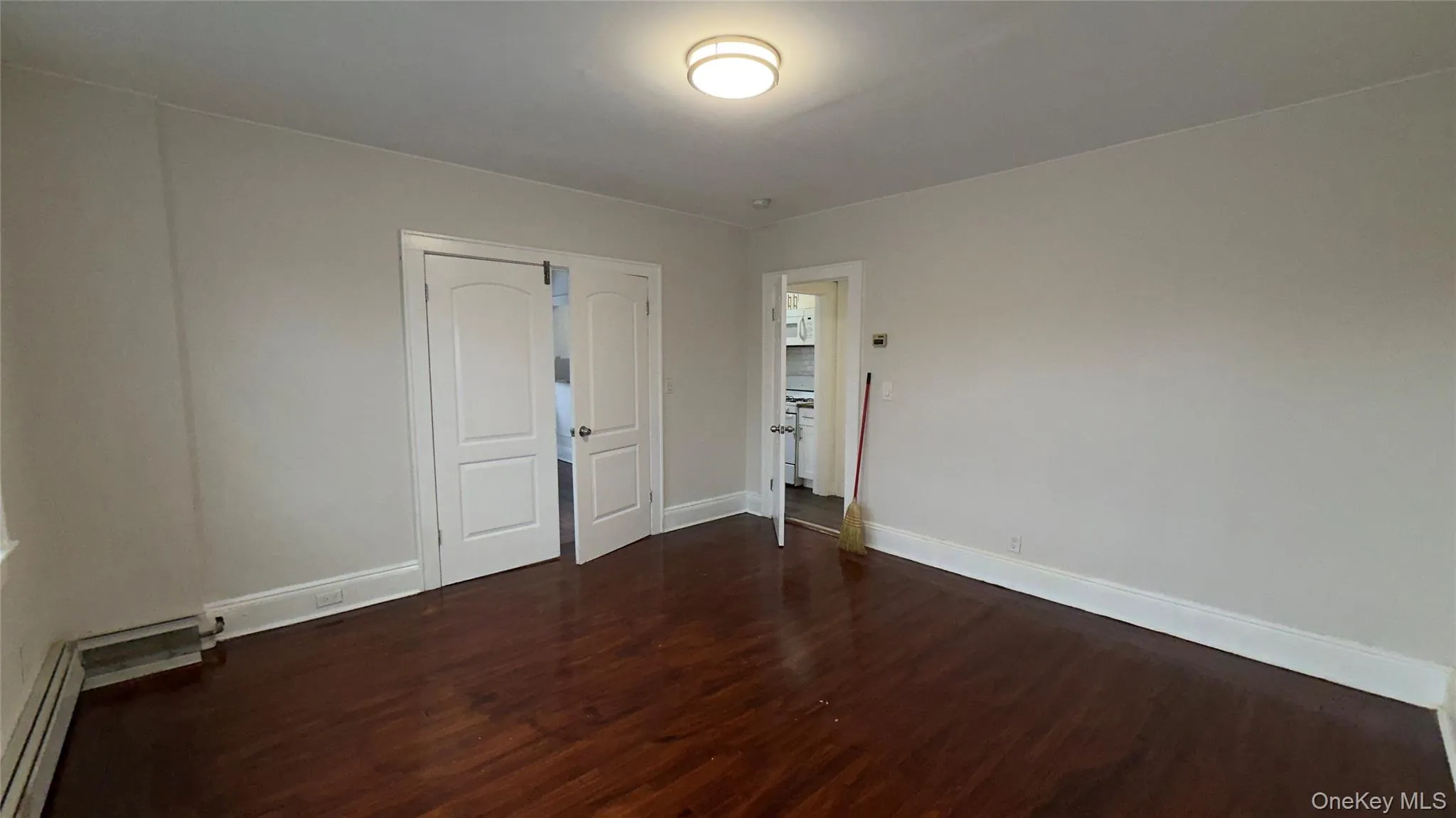 Spare room with dark wood-style floors and baseboard heating Spare room with dark wood-style floors and baseboard heating