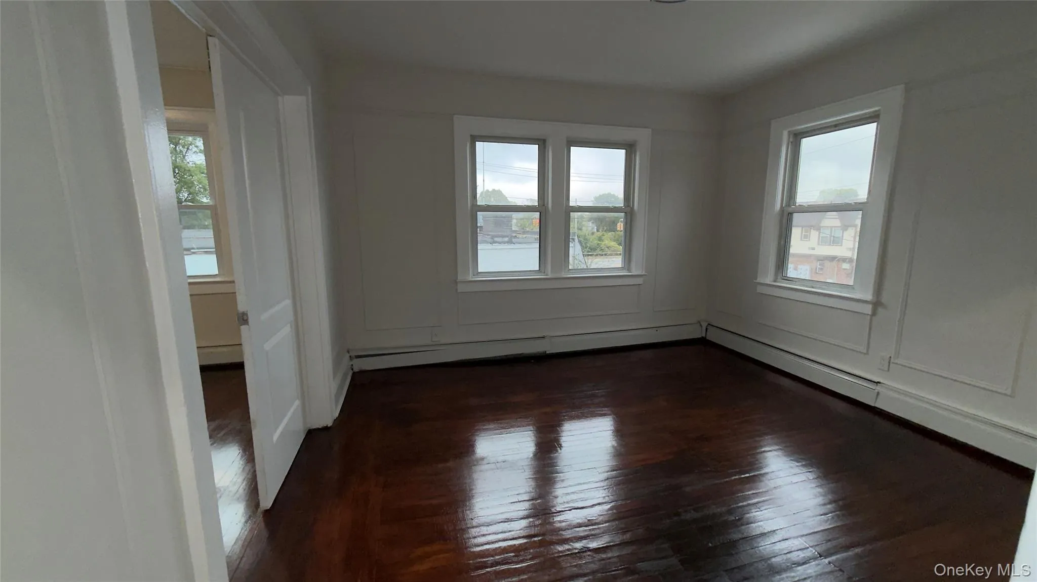 Unfurnished room featuring dark wood-style floors and a baseboard radiator Unfurnished room featuring dark wood-style floors and a baseboard radiator