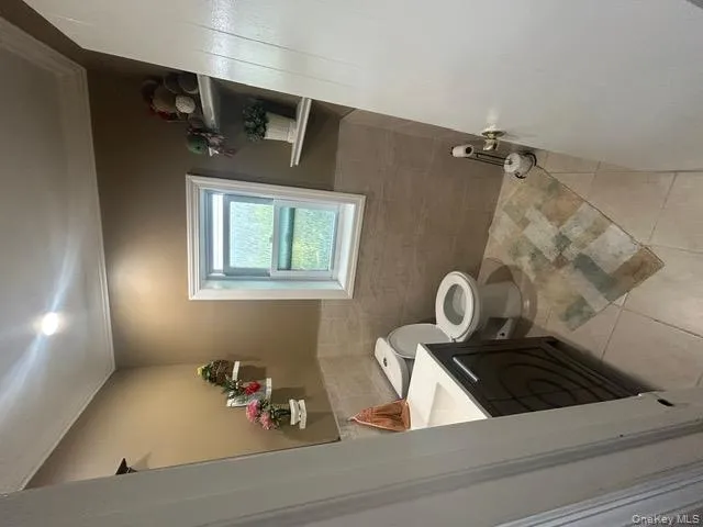 Bathroom with vanity, tile walls, ornamental molding, light tile patterned floors, and a wainscoted wall Bathroom with vanity, tile walls, ornamental molding, light tile patterned floors, and a wainscoted wall