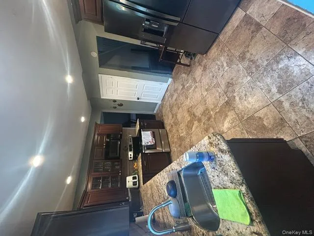 Kitchen with glass insert cabinets, appliances with stainless steel finishes, dark brown cabinetry, recessed lighting, and light stone countertops Kitchen with glass insert cabinets, appliances with stainless steel finishes, dark brown cabinetry, recessed lighting, and light stone countertops
