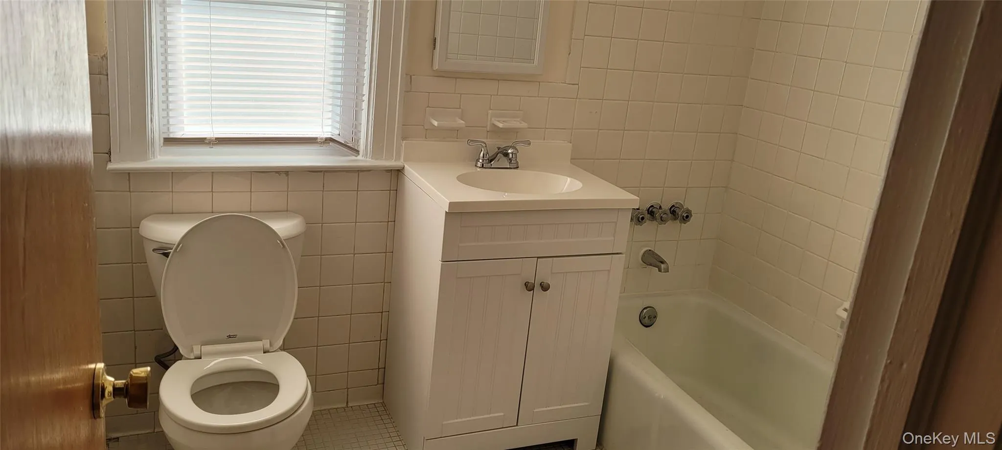 Bathroom featuring tile walls, vanity, shower / washtub combination, and tile patterned flooring Bathroom featuring tile walls, vanity, shower / washtub combination, and tile patterned flooring