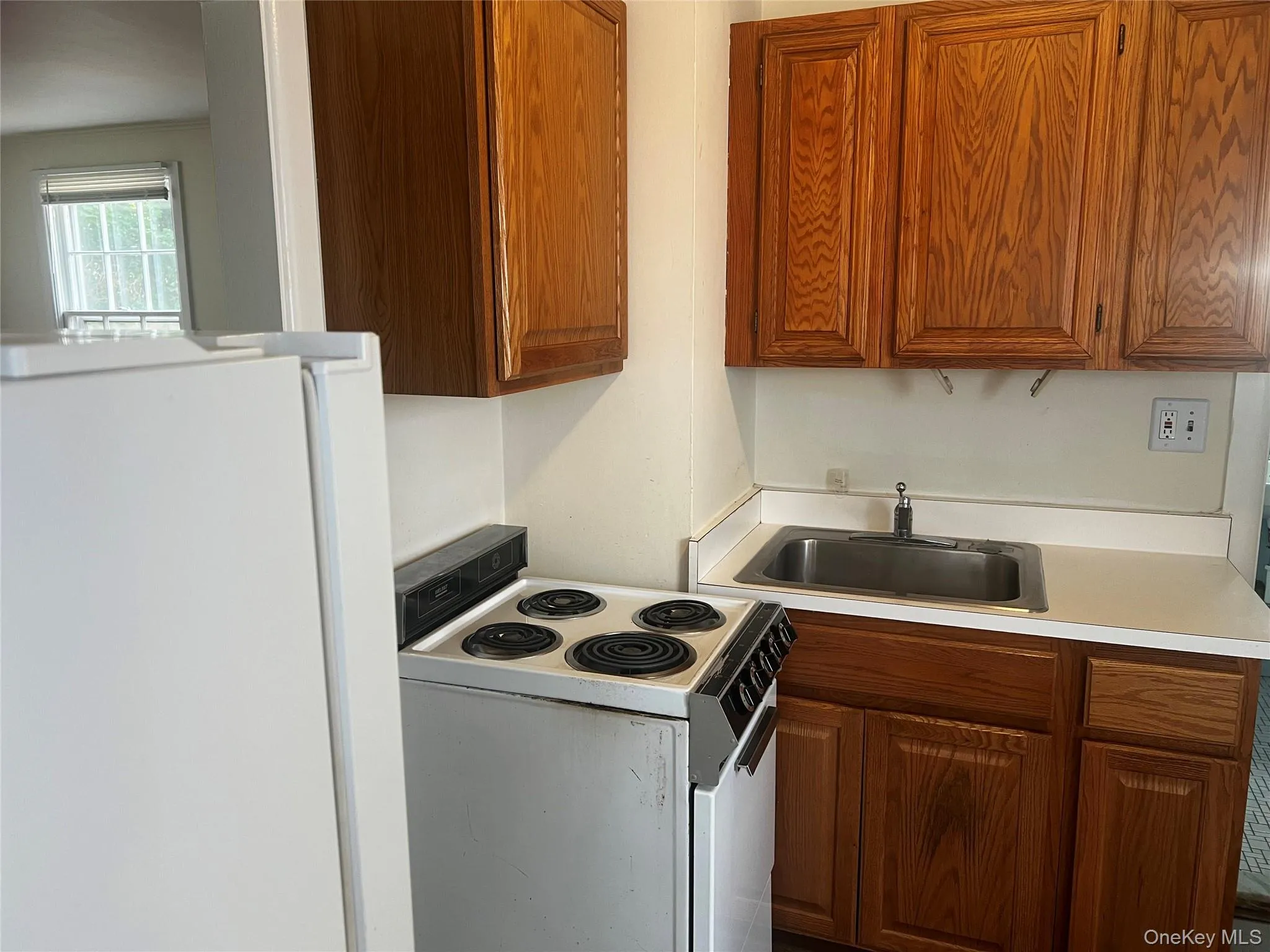 Kitchen with white appliances, light countertops, and brown cabinetry Kitchen with white appliances, light countertops, and brown cabinetry