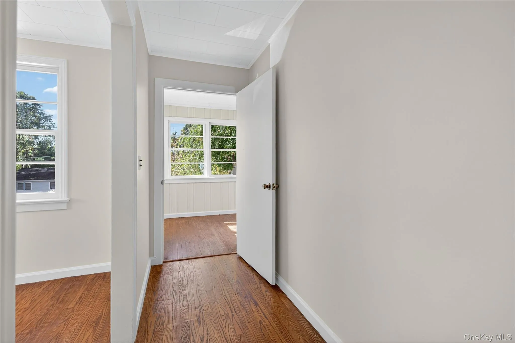 Hall featuring wood finished floors and ornamental molding Hall featuring wood finished floors and ornamental molding