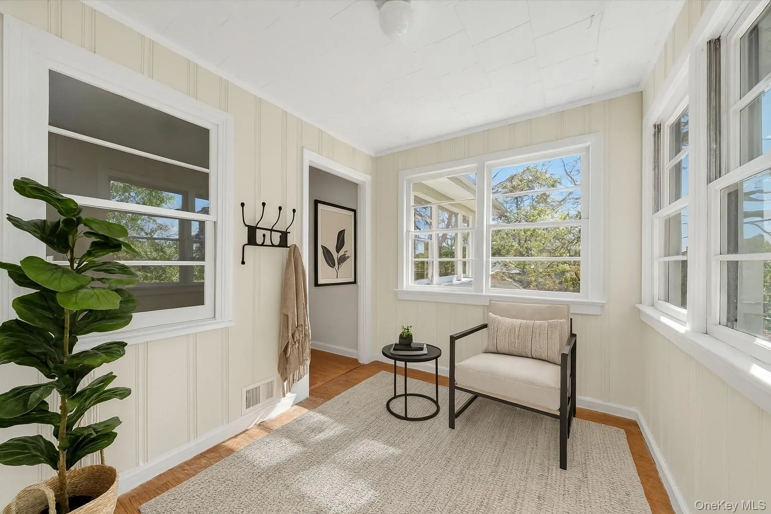 Living area featuring healthy amount of natural light, light wood-style flooring, and a decorative wall Living area featuring healthy amount of natural light, light wood-style flooring, and a decorative wall