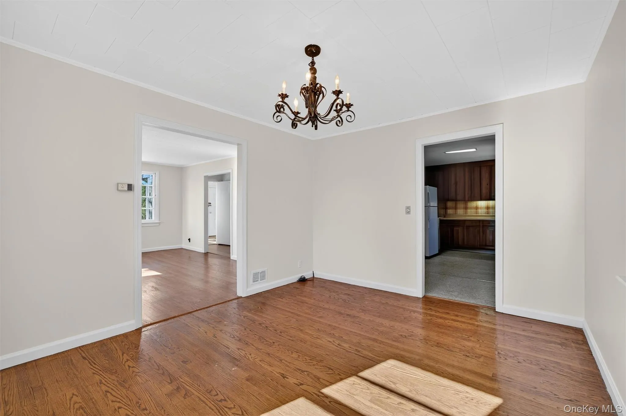 Spare room featuring a chandelier, wood finished floors, and ornamental molding Spare room featuring a chandelier, wood finished floors, and ornamental molding