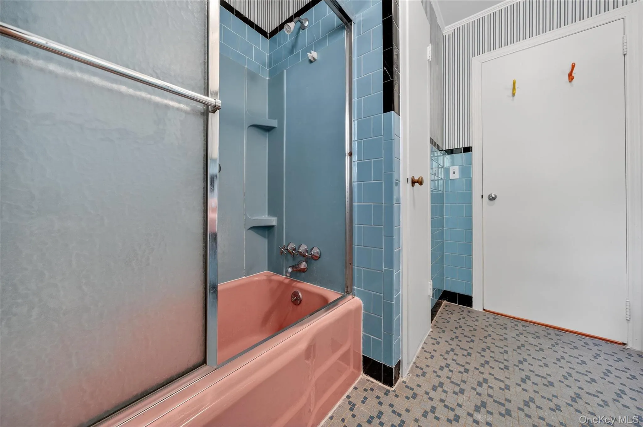 Bathroom with shower / bathtub combination, tile walls, and wallpapered walls Bathroom with shower / bathtub combination, tile walls, and wallpapered walls