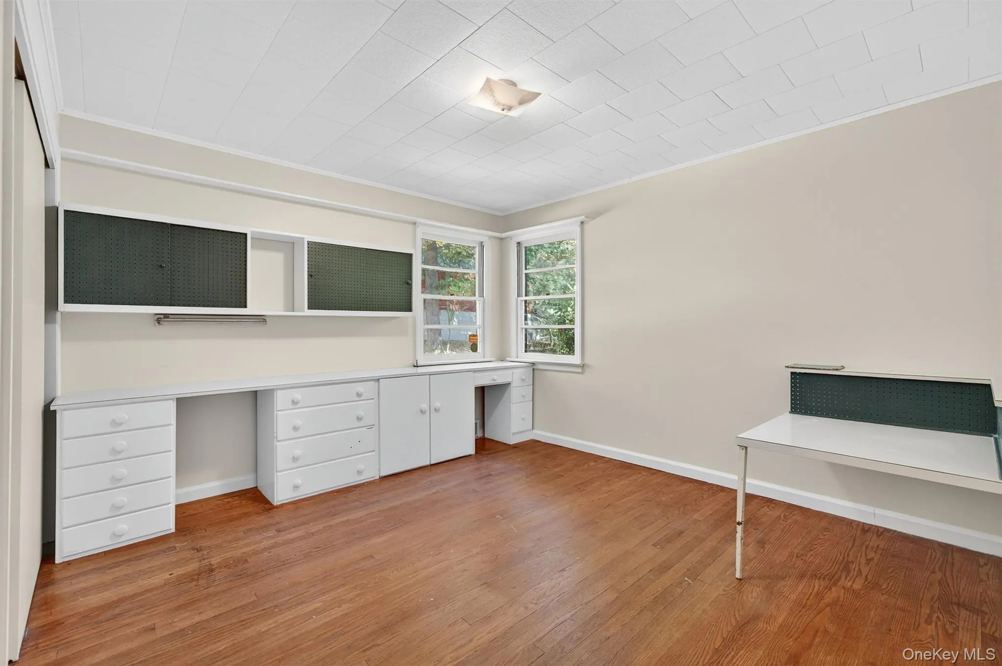 Unfurnished office featuring built in desk, light wood-type flooring, and ornamental molding Unfurnished office featuring built in desk, light wood-type flooring, and ornamental molding