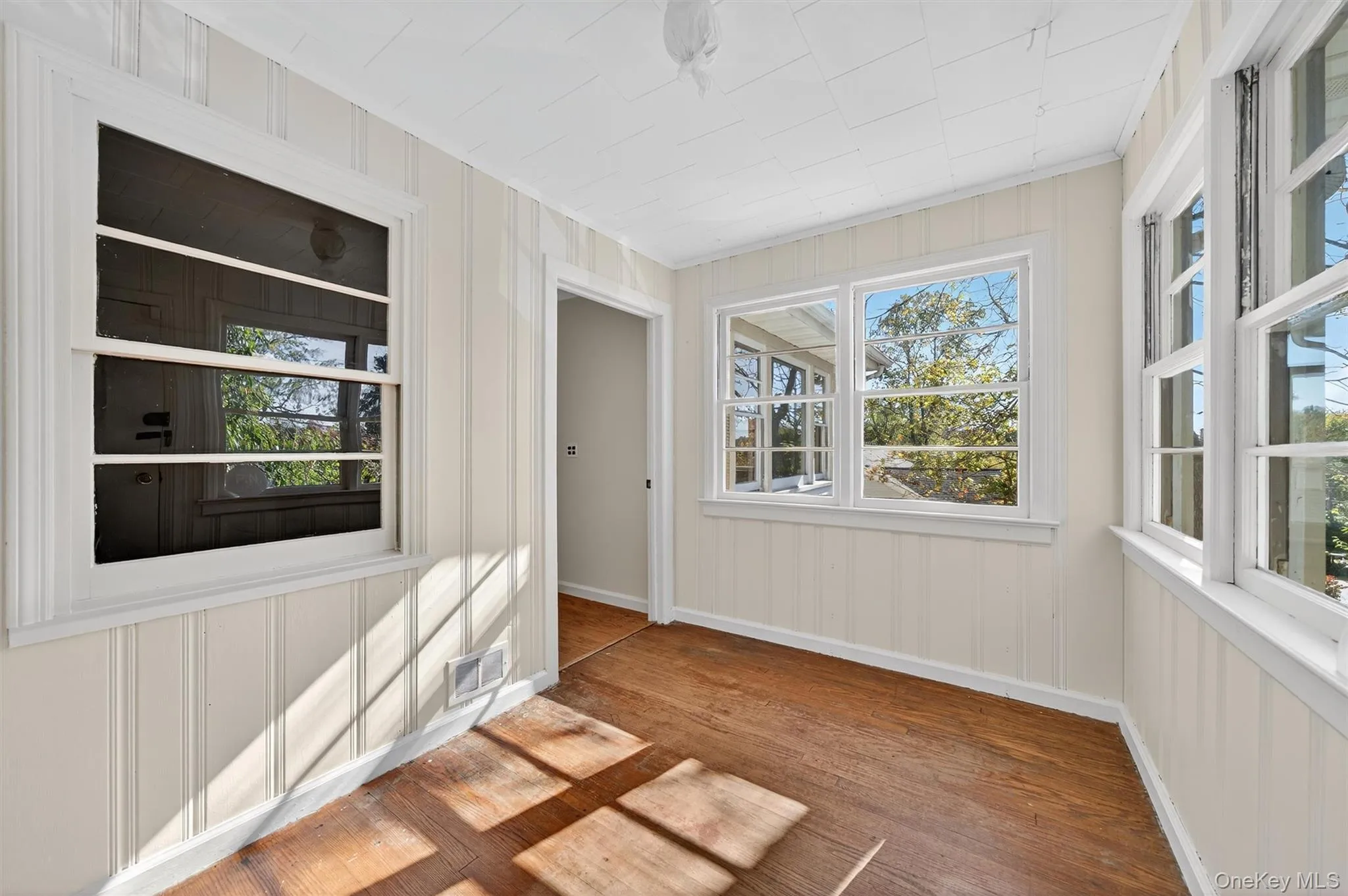 Unfurnished sunroom with wood finished floors and baseboards Unfurnished sunroom with wood finished floors and baseboards