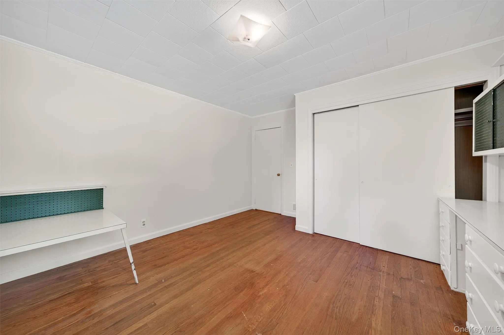 Unfurnished bedroom with dark wood finished floors, a closet, and ornamental molding Unfurnished bedroom with dark wood finished floors, a closet, and ornamental molding