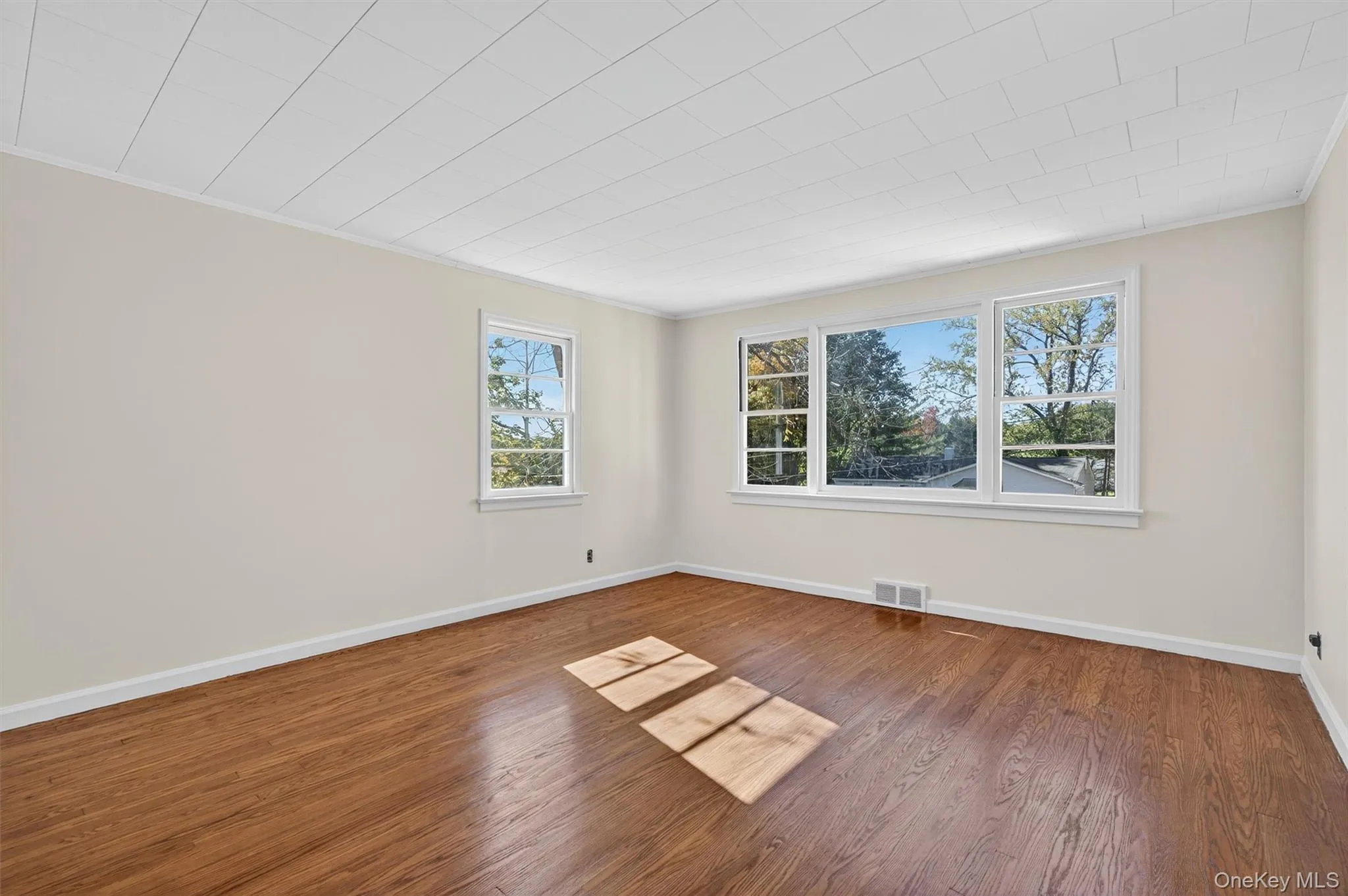 Unfurnished room featuring wood finished floors and ornamental molding Unfurnished room featuring wood finished floors and ornamental molding