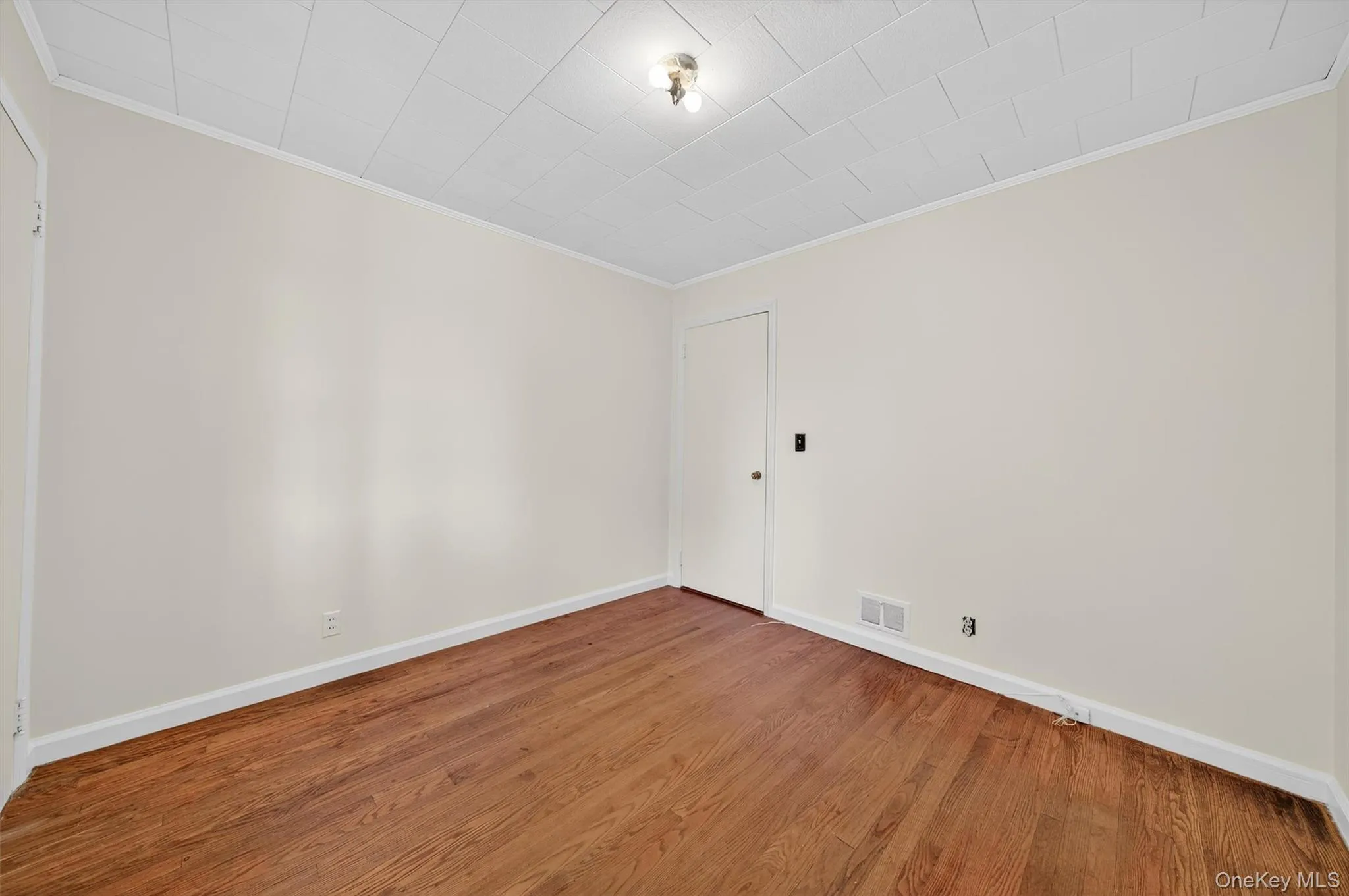 Empty room featuring wood finished floors and crown molding Empty room featuring wood finished floors and crown molding