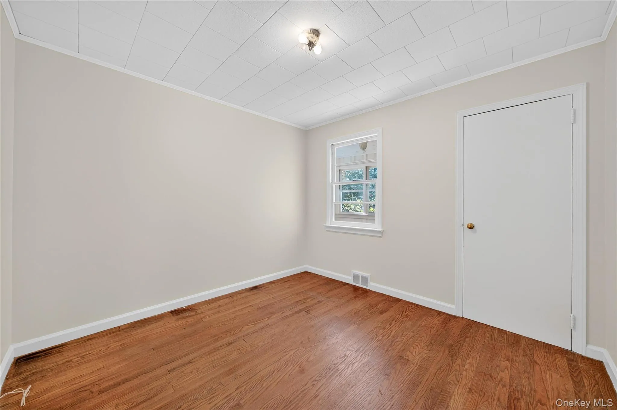 Unfurnished room with ornamental molding and wood finished floors Unfurnished room with ornamental molding and wood finished floors