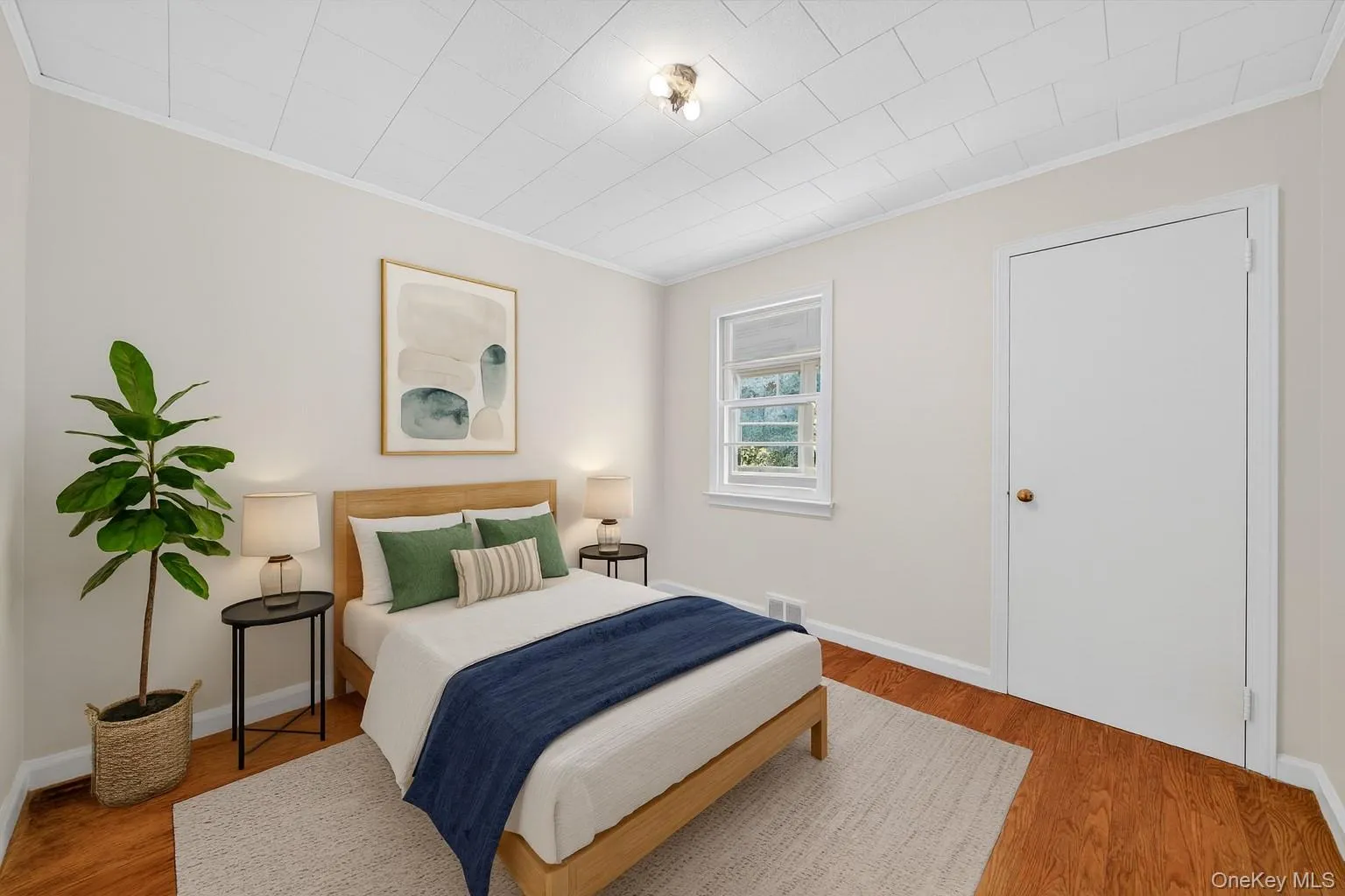 Bedroom with ornamental molding and wood finished floors Bedroom with ornamental molding and wood finished floors