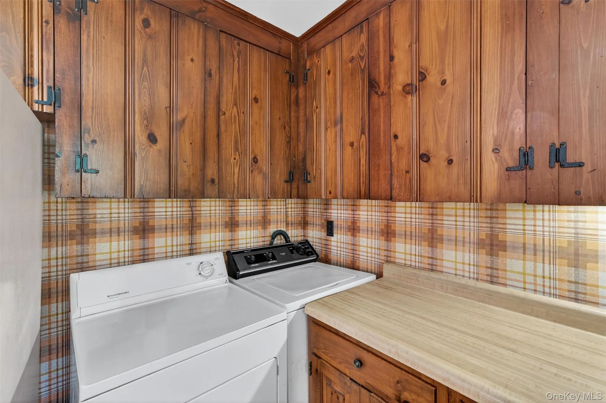 Laundry area with wallpapered walls and washer and clothes dryer Laundry area with wallpapered walls and washer and clothes dryer