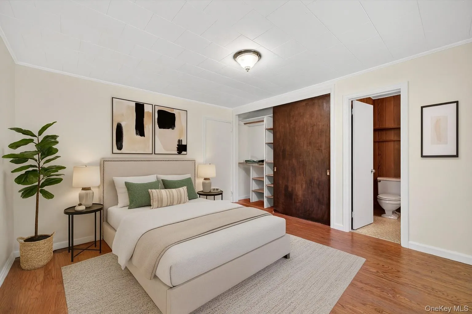 Bedroom featuring ornamental molding, a closet, and wood finished floors Bedroom featuring ornamental molding, a closet, and wood finished floors