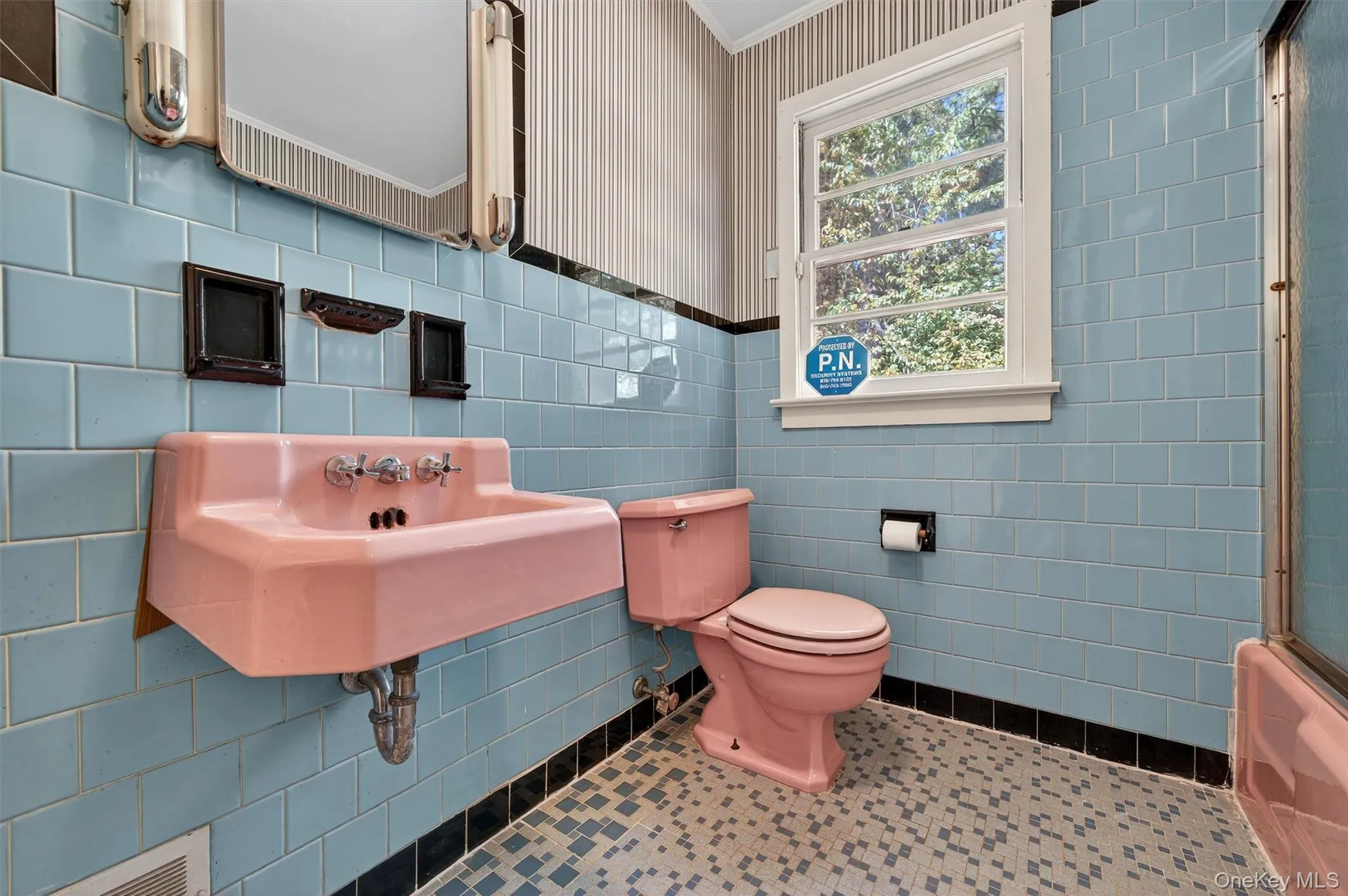 Bathroom featuring tile patterned flooring, tile walls, bath / shower combo with glass door, and wallpapered walls Bathroom featuring tile patterned flooring, tile walls, bath / shower combo with glass door, and wallpapered walls