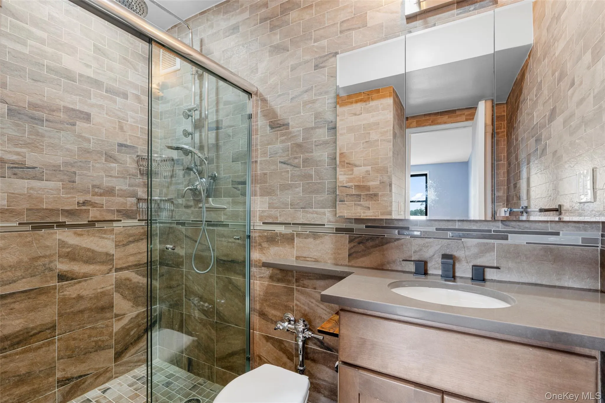 Bathroom featuring tile walls, vanity, and a shower stall Bathroom featuring tile walls, vanity, and a shower stall