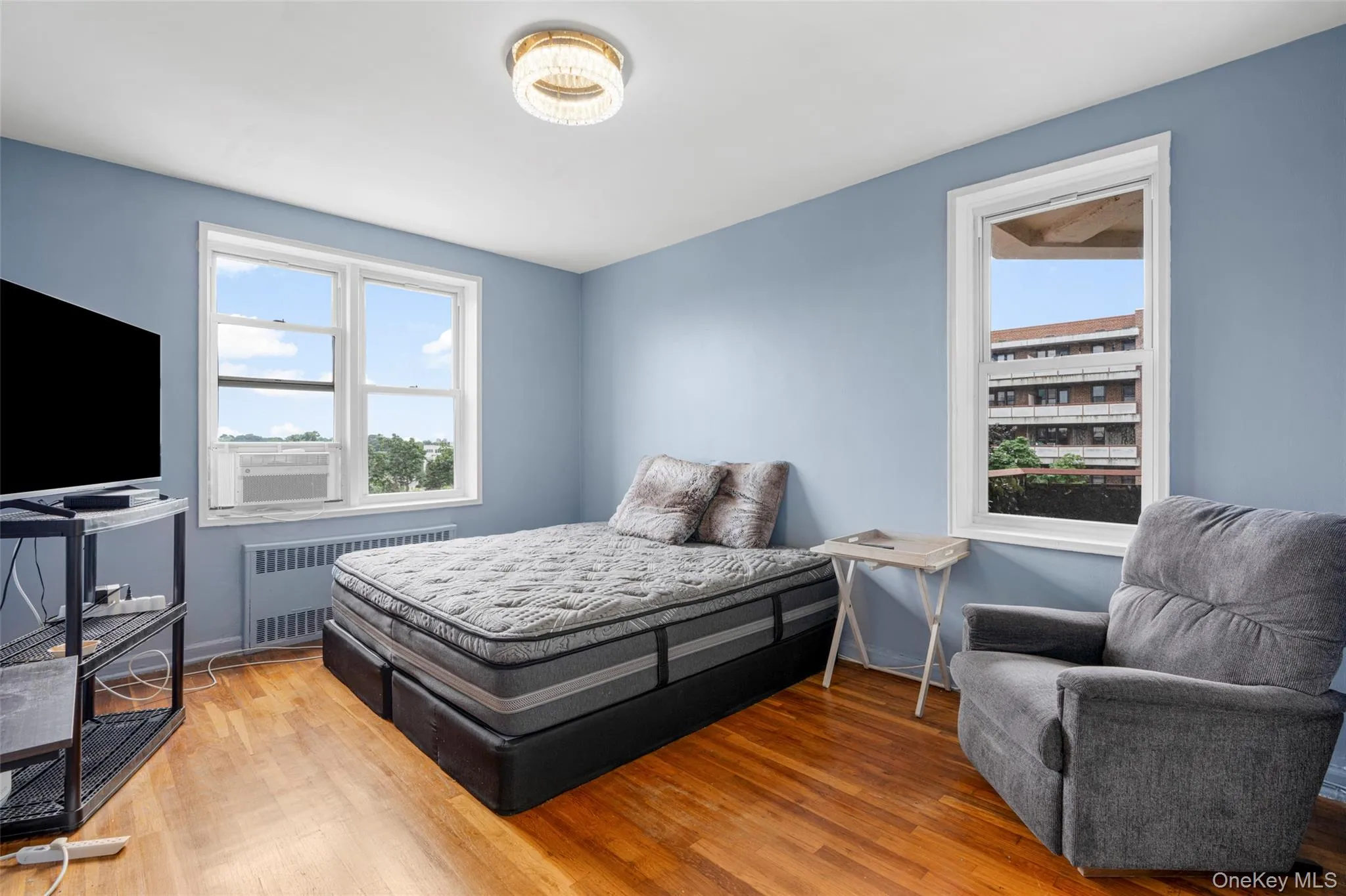 Bedroom with radiator heating unit and wood finished floors Bedroom with radiator heating unit and wood finished floors