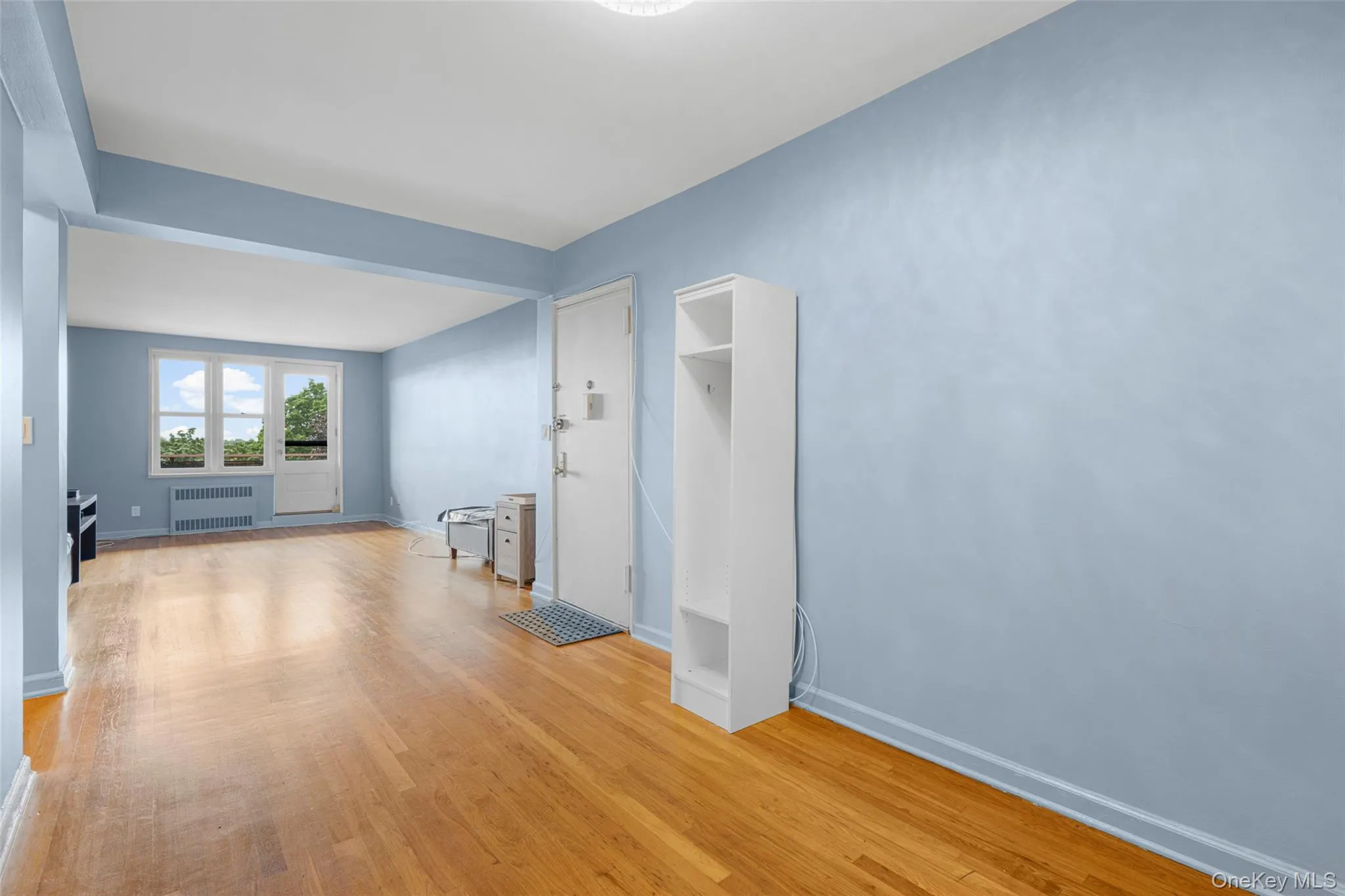 Unfurnished living room featuring light wood-style flooring and radiator Unfurnished living room featuring light wood-style flooring and radiator