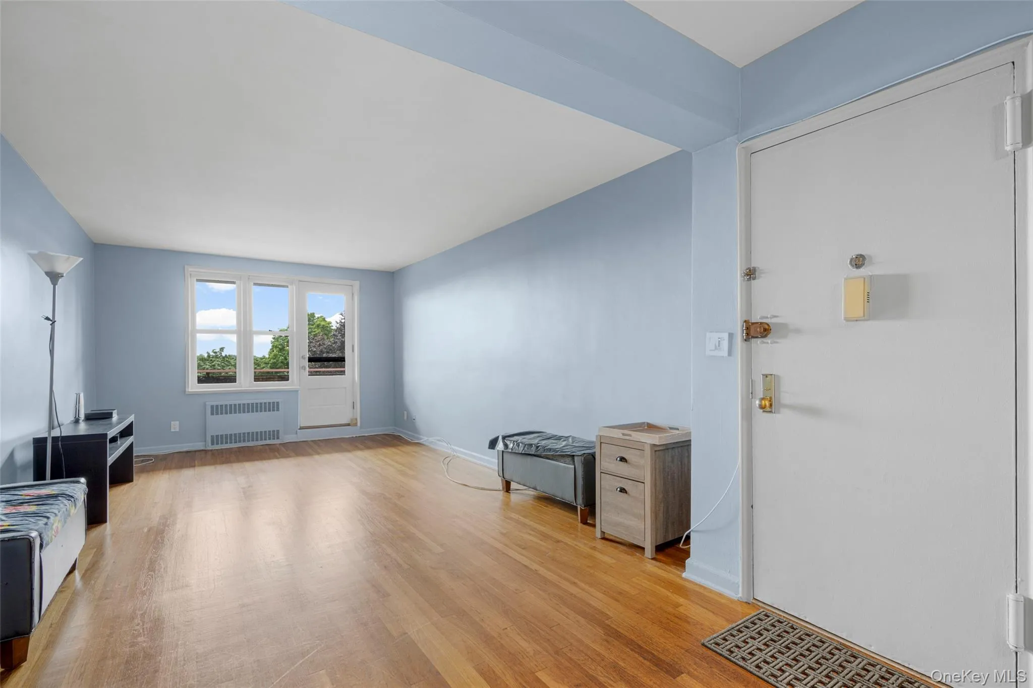 Unfurnished living room featuring light wood-style flooring and radiator heating unit Unfurnished living room featuring light wood-style flooring and radiator heating unit