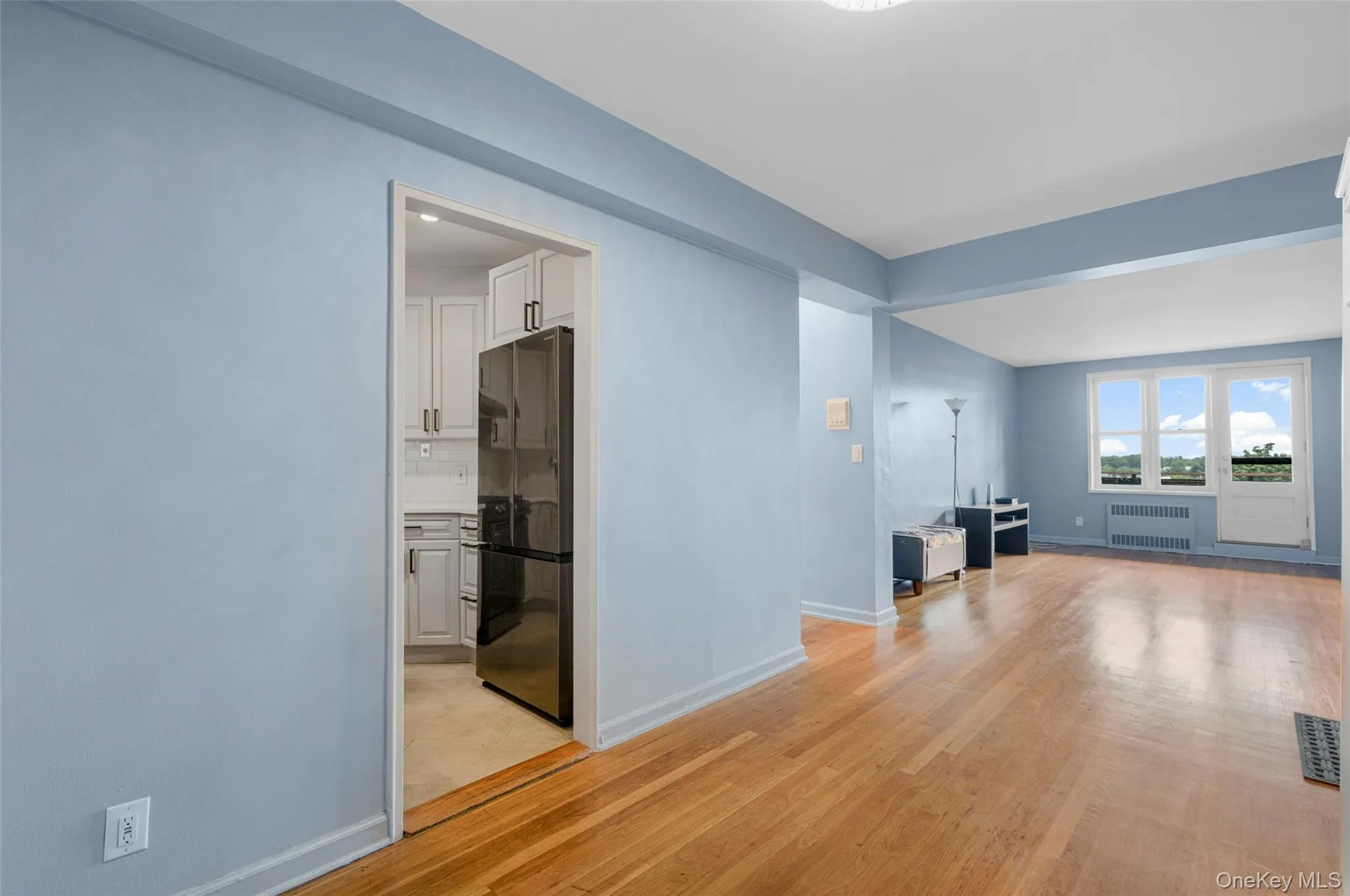 Unfurnished living room with light wood finished floors and radiator Unfurnished living room with light wood finished floors and radiator