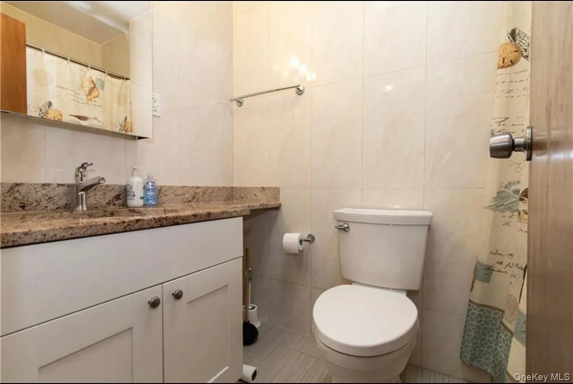 Bathroom with tile walls, vanity, curtained shower, and tile patterned floors Bathroom with tile walls, vanity, curtained shower, and tile patterned floors