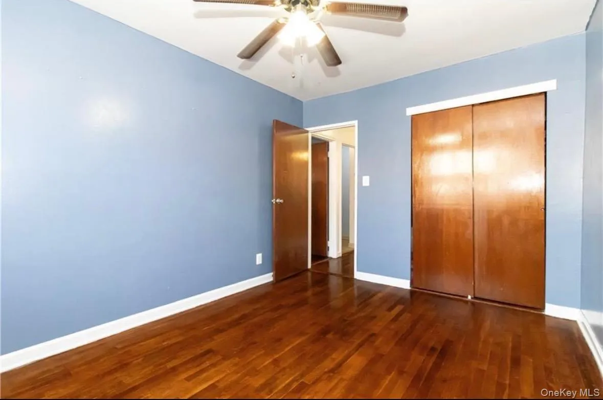 Unfurnished bedroom with dark wood-type flooring, a ceiling fan, and a closet Unfurnished bedroom with dark wood-type flooring, a ceiling fan, and a closet