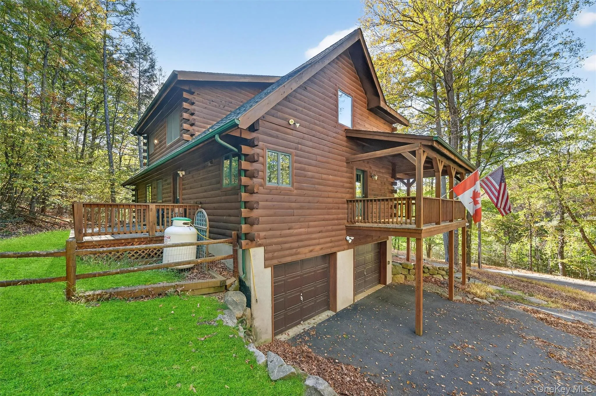 View of side of property with log exterior, a deck, a garage, and asphalt driveway View of side of property with log exterior, a deck, a garage, and asphalt driveway