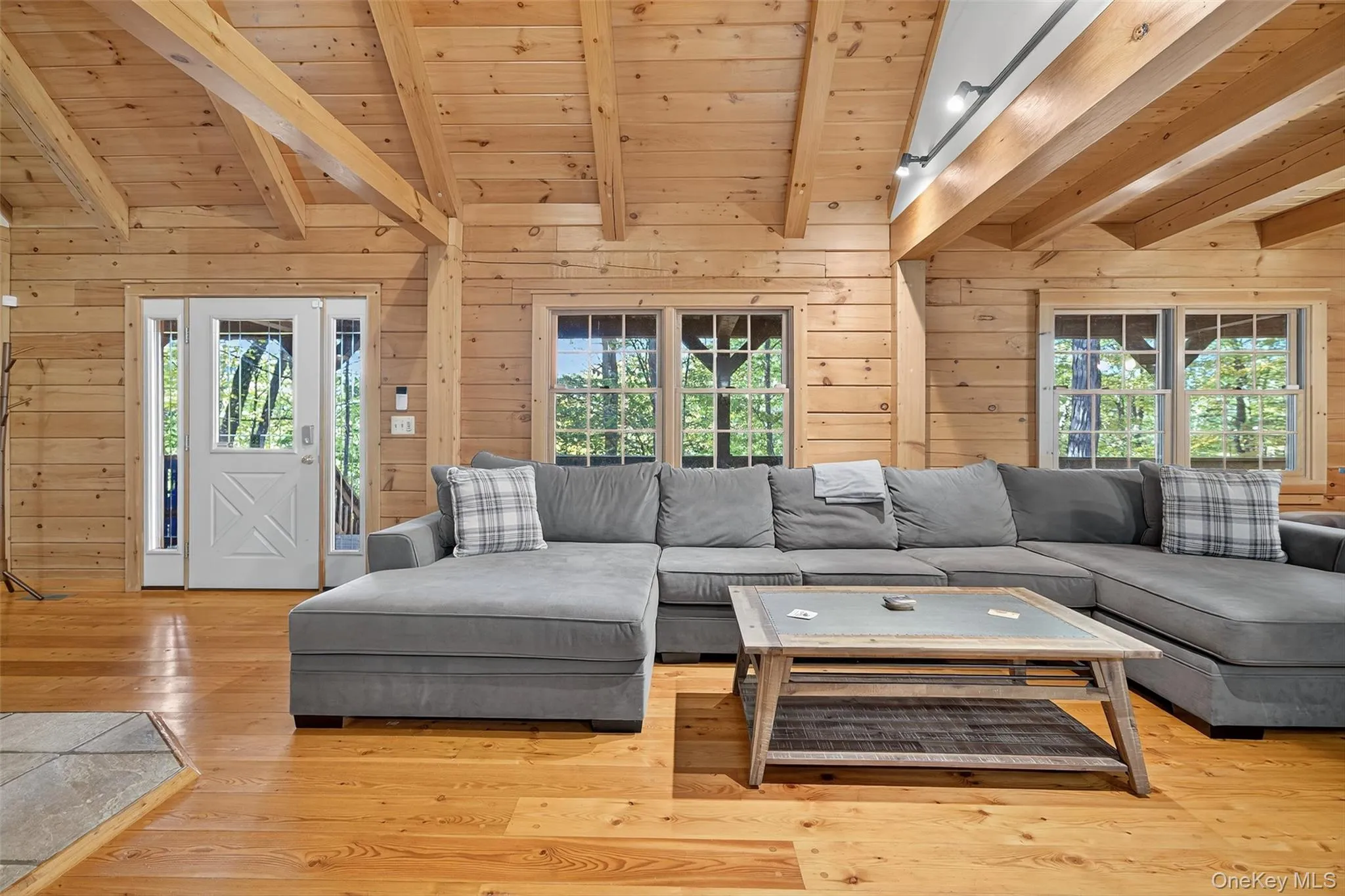 Living area with wooden walls, light wood-type flooring, wooden ceiling, and plenty of natural light Living area with wooden walls, light wood-type flooring, wooden ceiling, and plenty of natural light