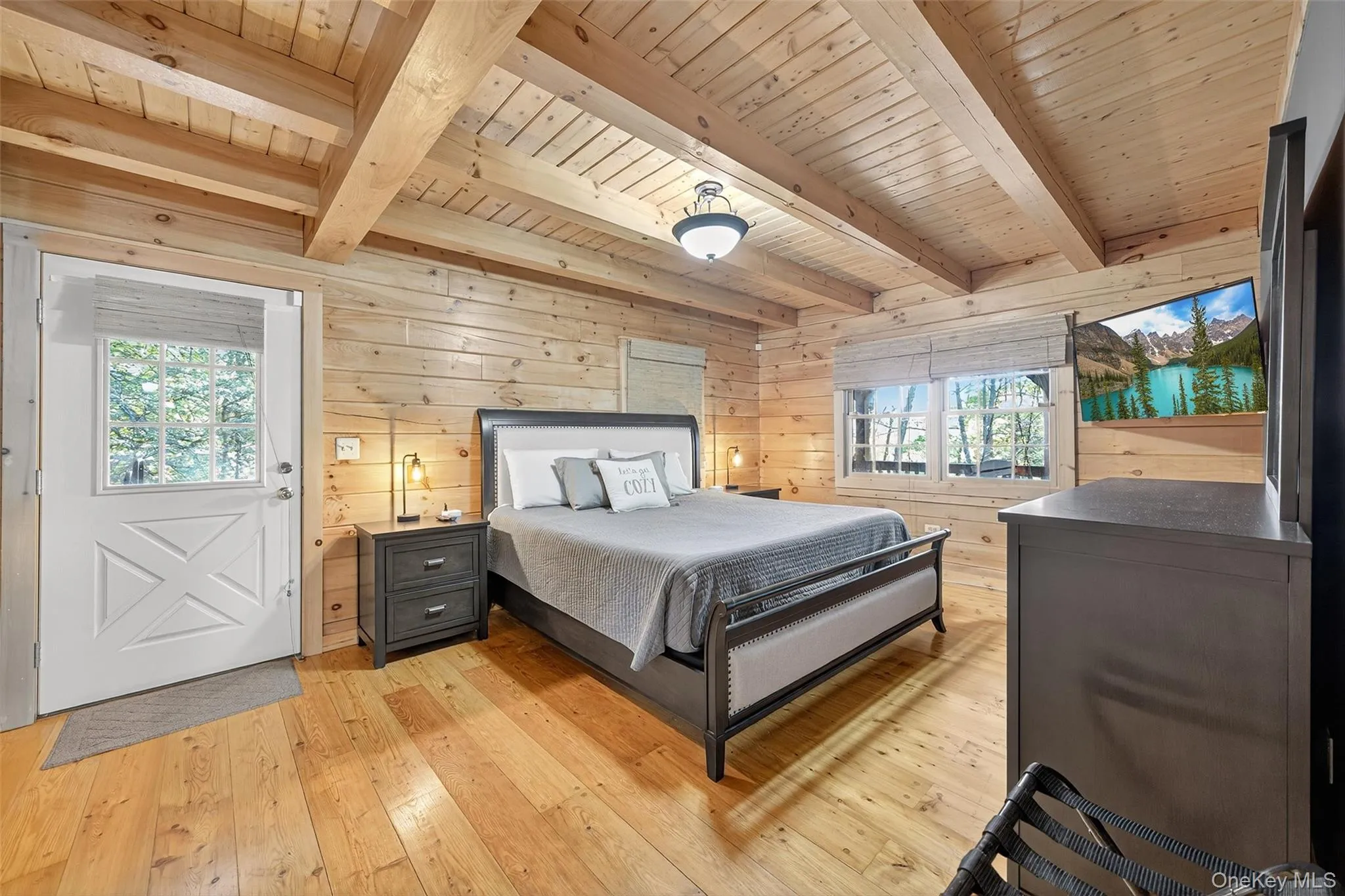 Bedroom with wooden walls, light wood-type flooring, and beam ceiling Bedroom with wooden walls, light wood-type flooring, and beam ceiling