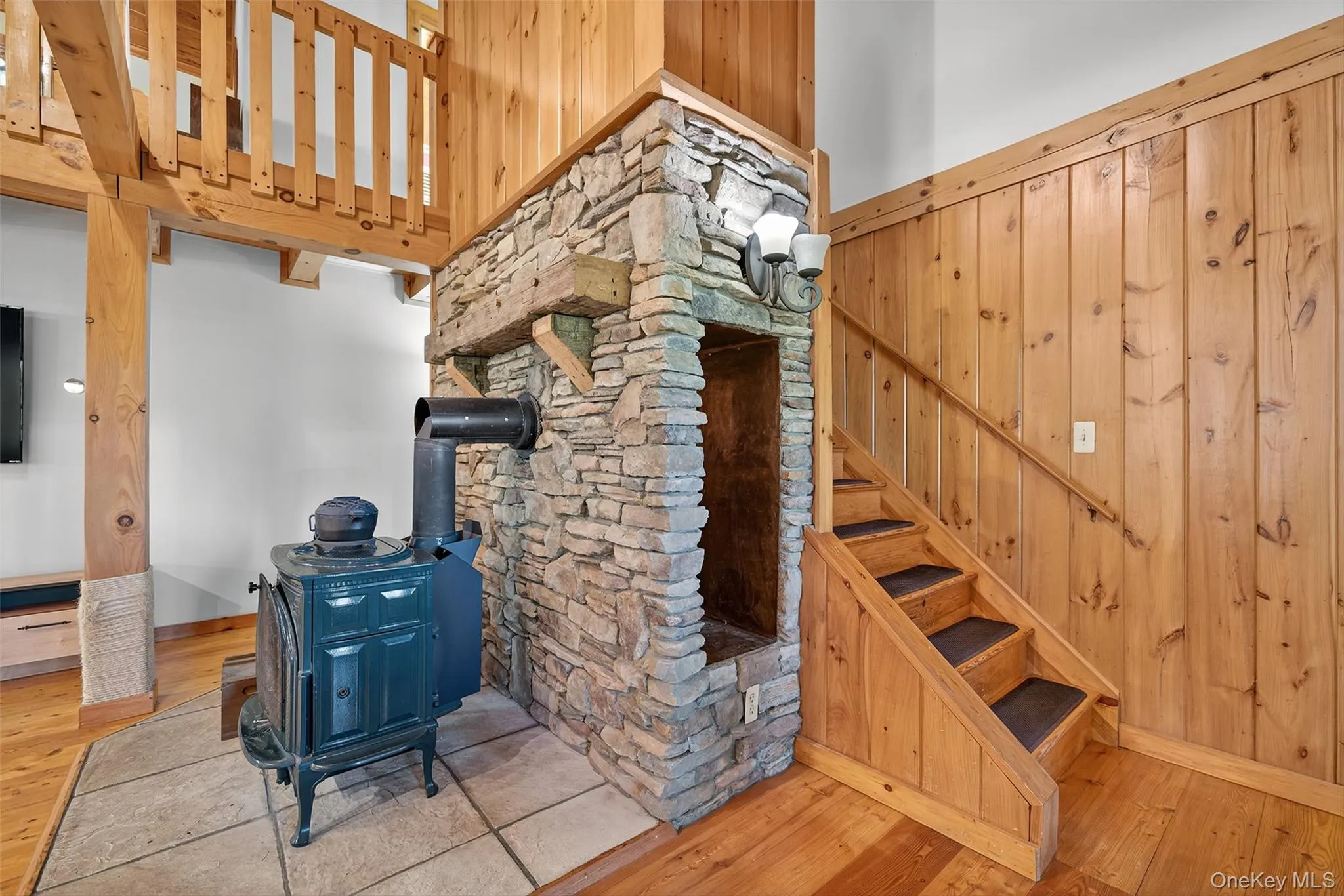 Stairs featuring wood walls, hardwood / wood-style flooring, and a wood stove Stairs featuring wood walls, hardwood / wood-style flooring, and a wood stove