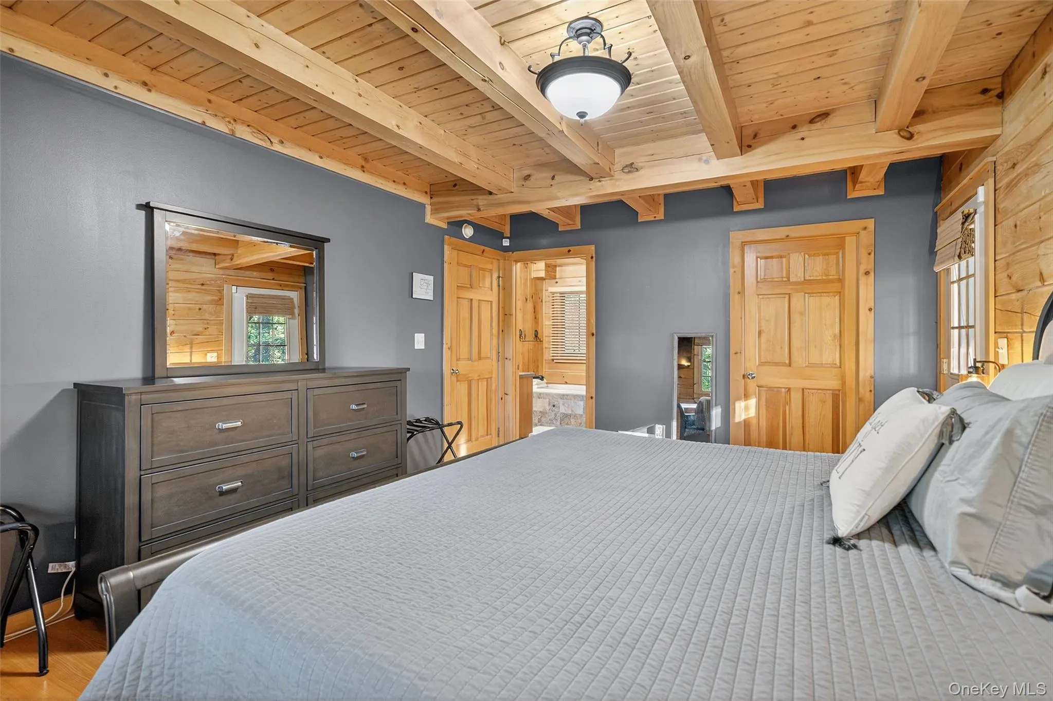Bedroom featuring a wooden ceiling with exposed beams, light wood-style flooring, and ensuite bathroom Bedroom featuring a wooden ceiling with exposed beams, light wood-style flooring, and ensuite bathroom
