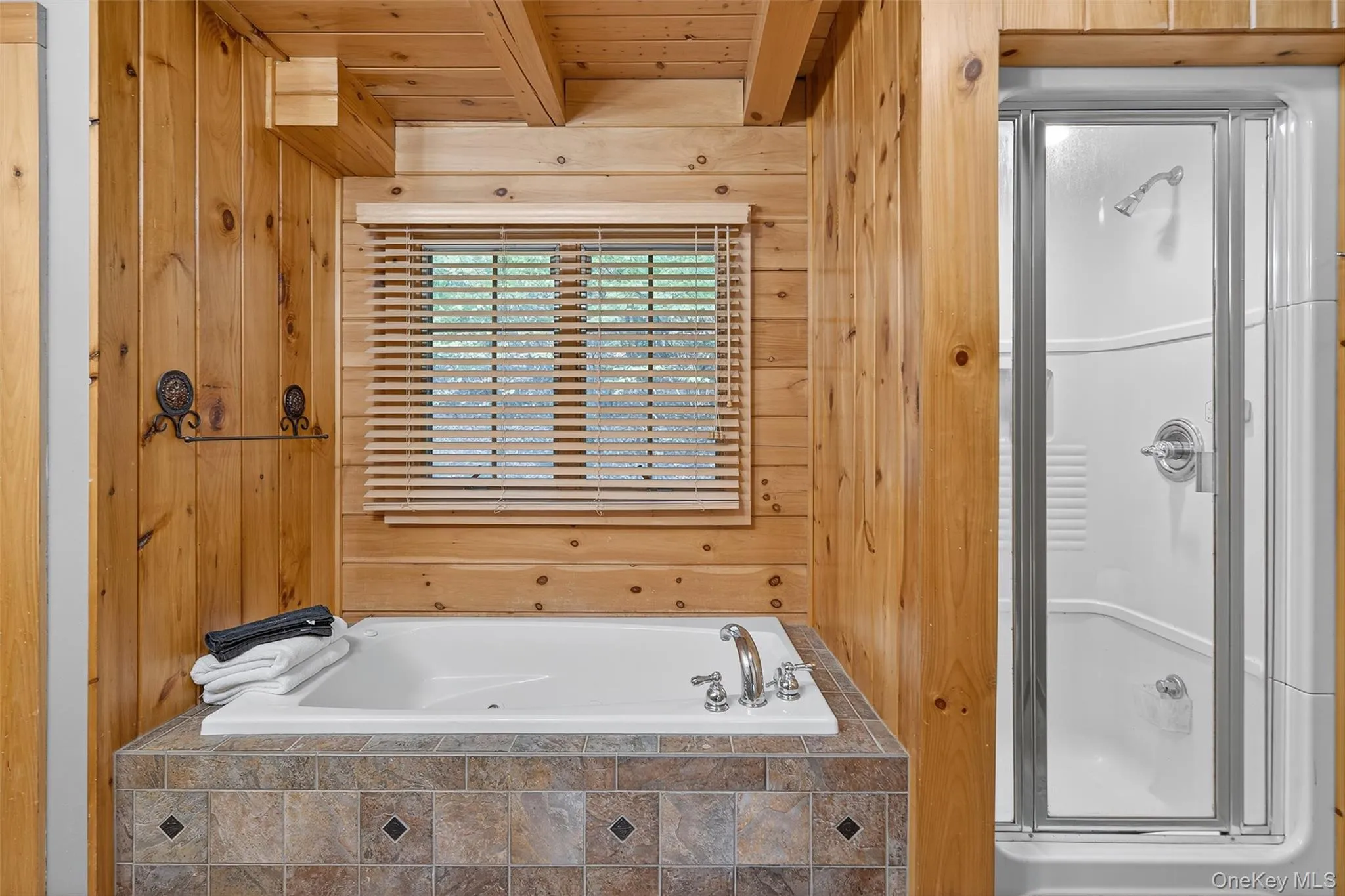Full bathroom with wooden walls, a stall shower, a wooden ceiling with exposed beams, and a garden tub Full bathroom with wooden walls, a stall shower, a wooden ceiling with exposed beams, and a garden tub